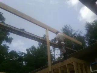 Carpenter setting a ridge beam over a new addition frame — Ice Dam Removal by Roofing Brothers in Ligonier