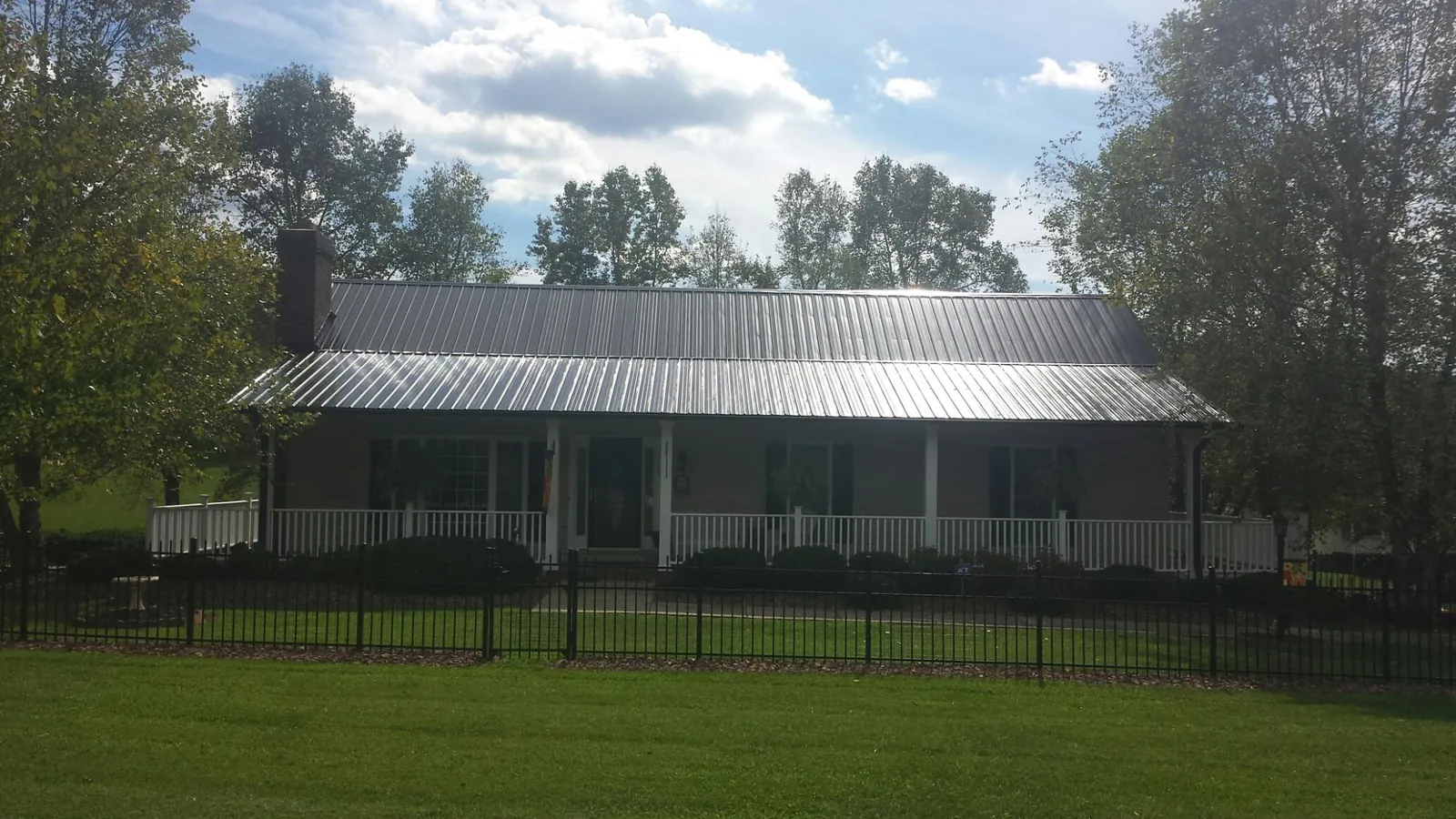 Gray metal roof on a brick ranch with a full width front porch — Gutter Guard Installation work by our crew in Ligonier